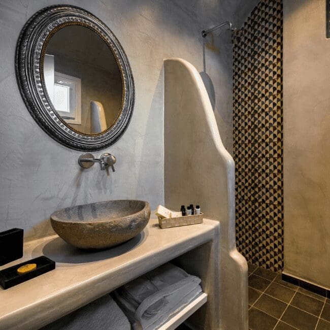 Bathroom with a stone basin, round mirror and textured wall in the Suite with Indoor Hot Tub