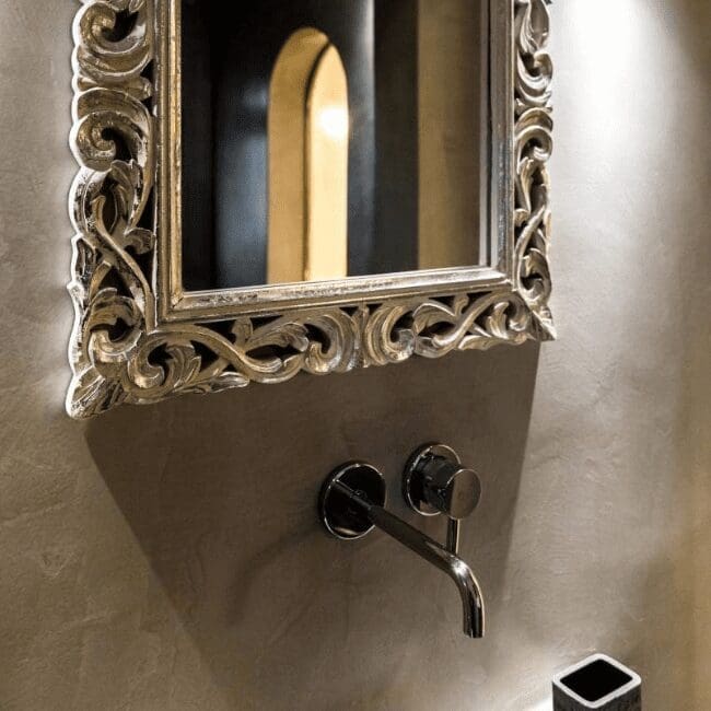 Ornate silver-framed mirror and wall-mounted tap in a boutique suite bathroom at Emerald Collection Suites, Santorini