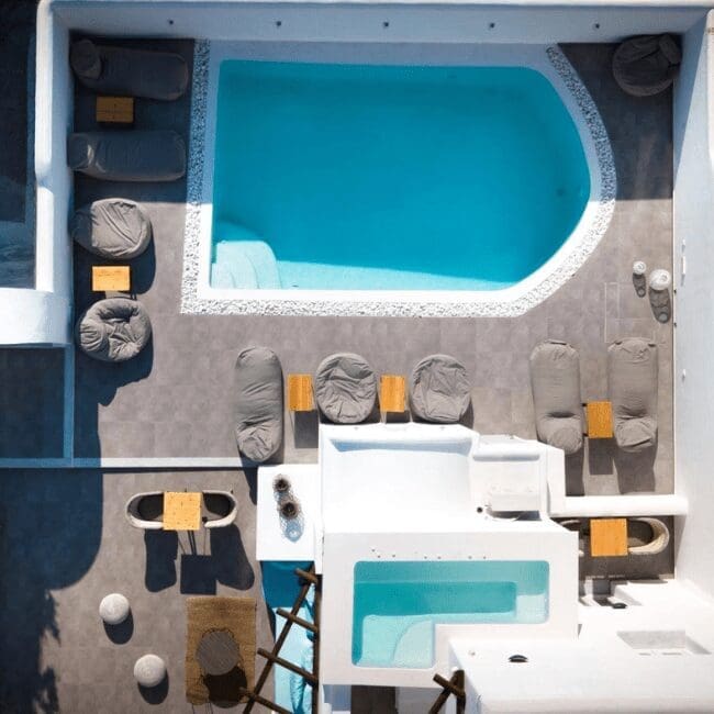 Aerial view of the outdoor swimming pool and relaxation area at Emerald Collection Suites, Karterados Santorini