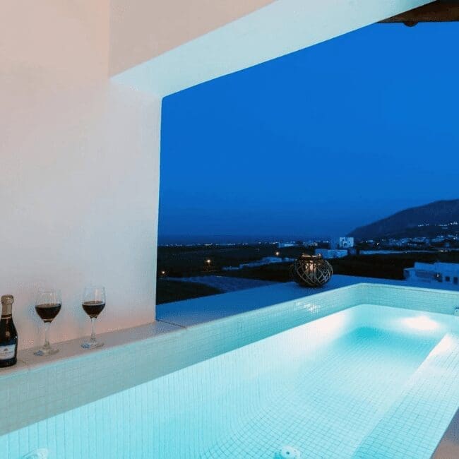 Private outdoor hot tub with wine glasses and open view of Santorini landscape at dusk, Emerald Collection Suites