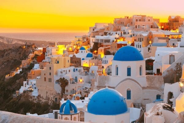 Oia village at sunset with blue-domed churches above the Santorini caldera